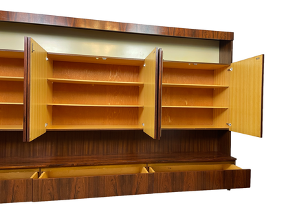 Angled view of the wall unit's open cabinets, light-wood interiors, shelves, display niche, and drawers.