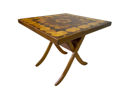 Angled view showing the marquetry surface, worn wood edge, folding base, and curved feet.