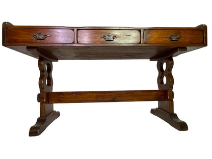 Detail of the trestle base and carved supports on an antique Victorian solid pine writing desk.