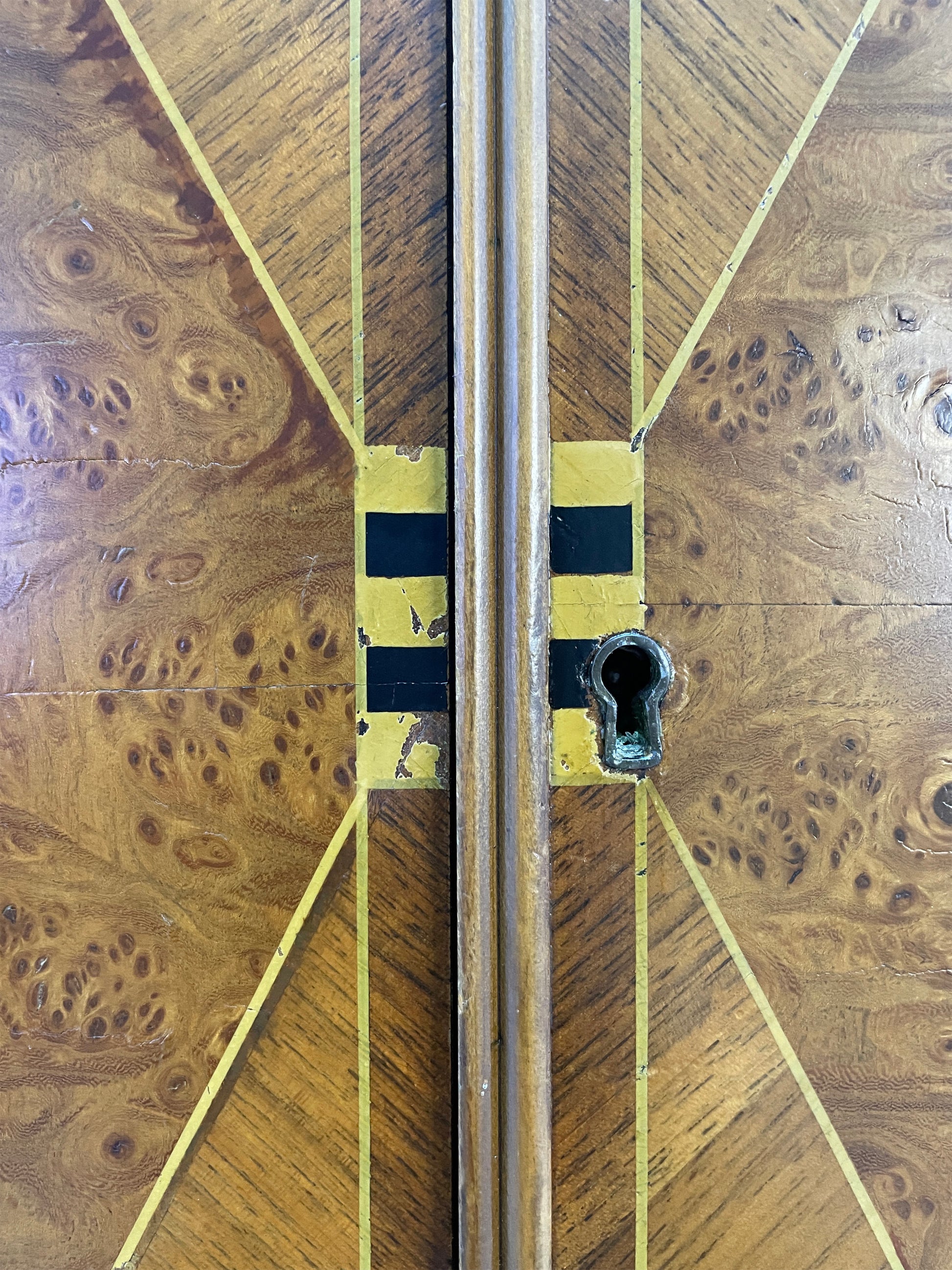 Close-up of Art Deco inlay design and keyhole on cabinet doors with burl wood pattern