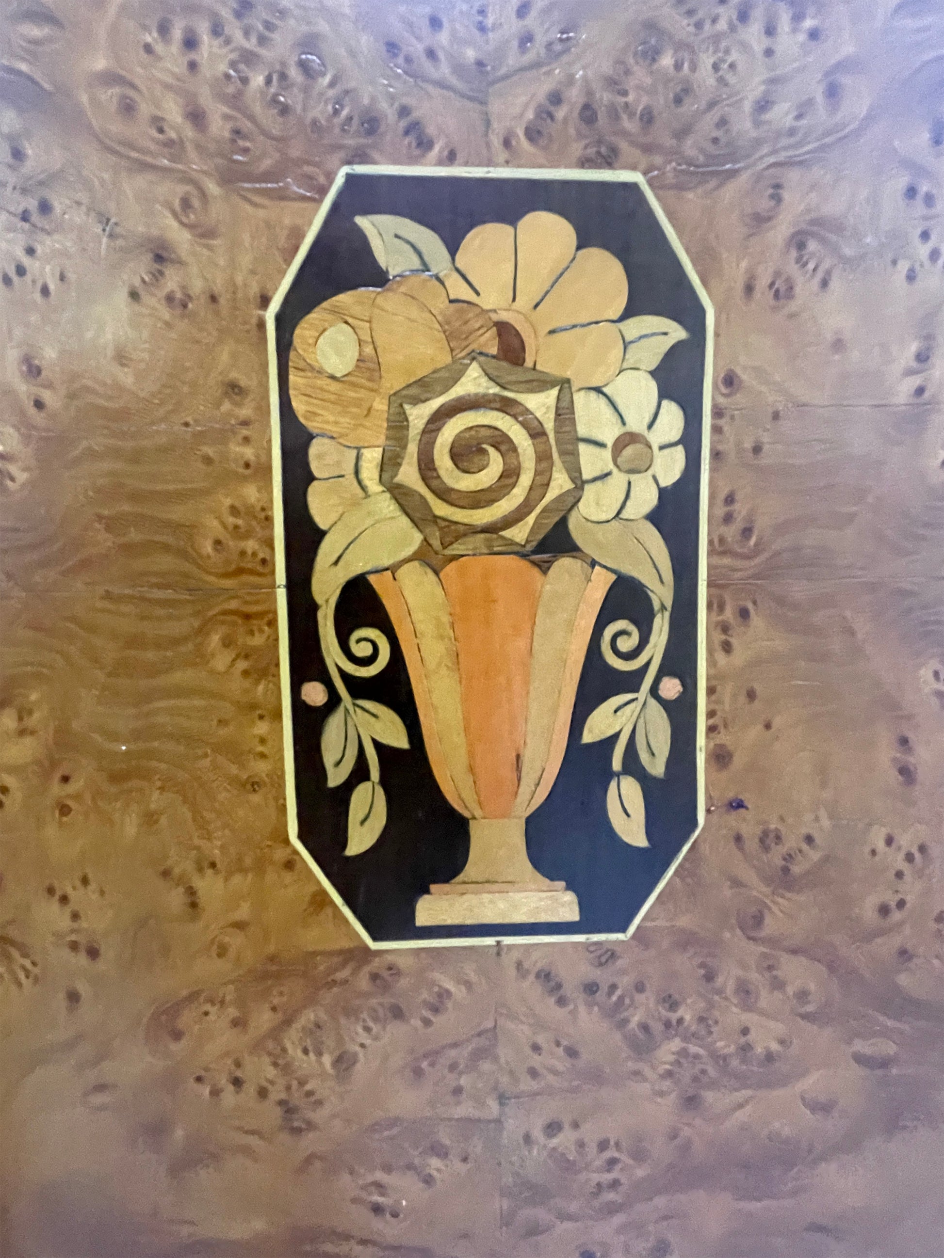 Detailed marquetry vase motif on cabinet door featuring contrasting wood inlay