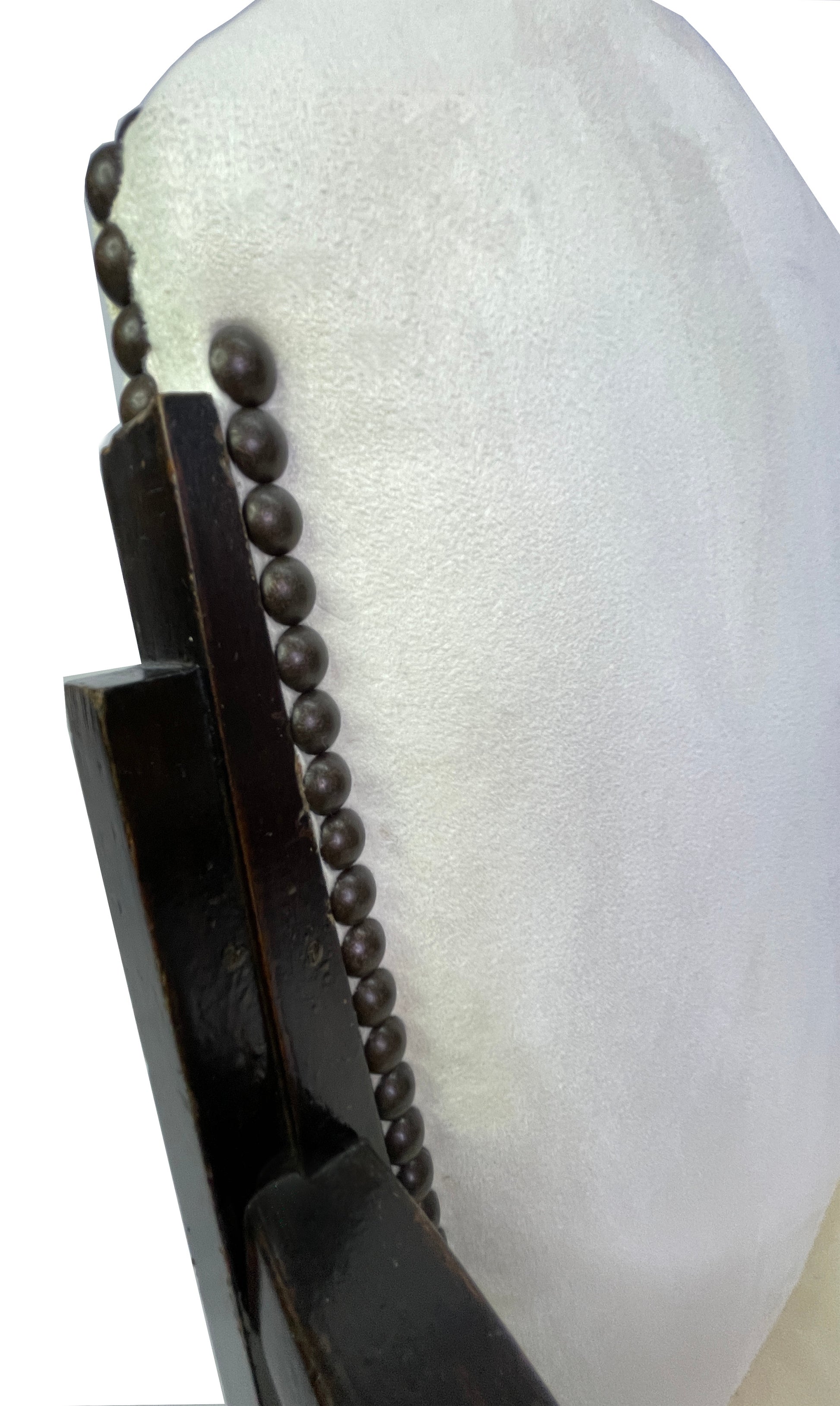 Close-up detail of ivory suede-like upholstery and decorative nailhead trim on a vintage Art Deco style dining chair.