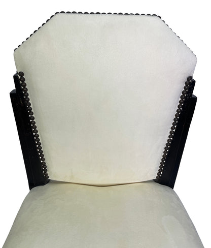 Close-up detail of a vintage Art Deco style side chair featuring ivory suede-like upholstery and decorative nailhead trim.