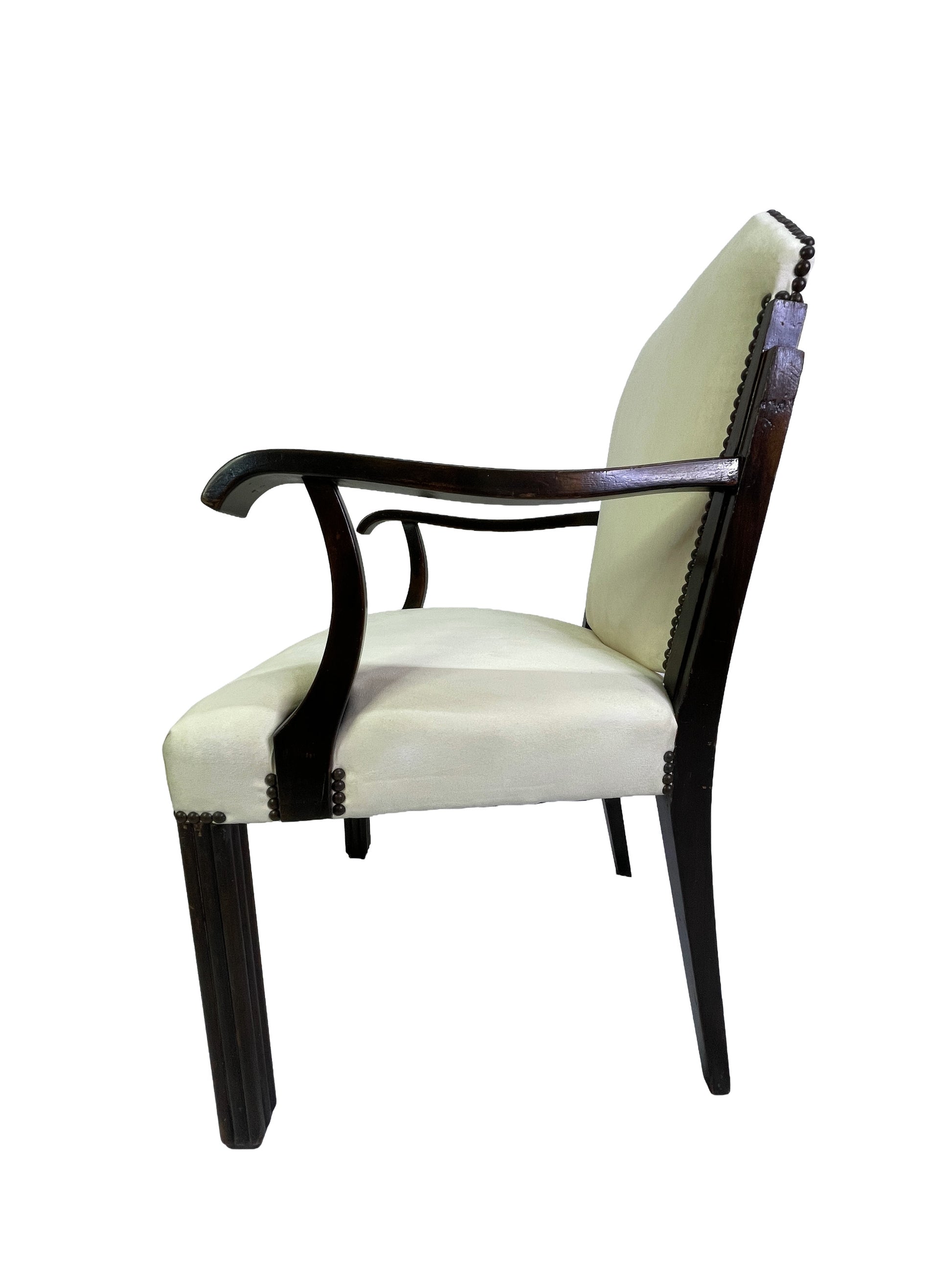 Side view of a vintage Art Deco style arm chair with curved wooden arms, ivory upholstery, and dark mahogany frame.