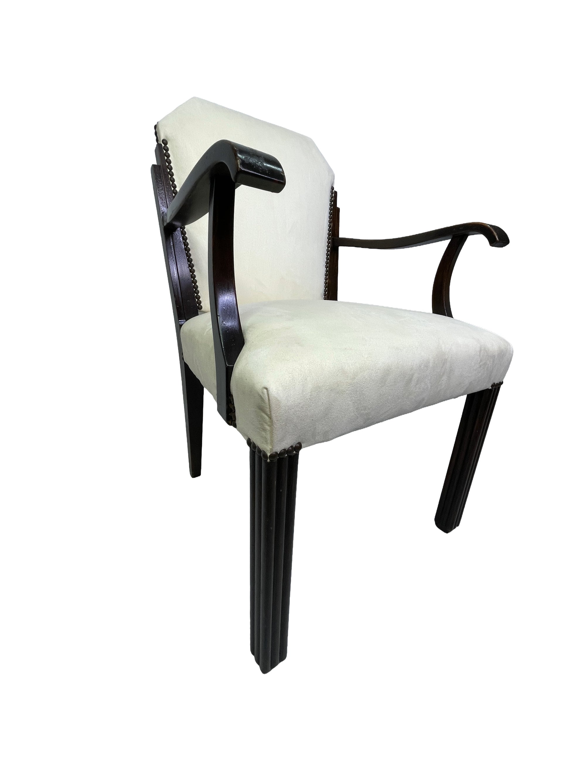 Three-quarter view of a vintage Art Deco style dining armchair with ivory upholstery, curved wooden arms, nailhead trim, and dark mahogany legs.