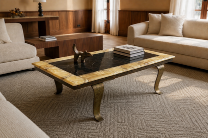 Luxury lifestyle image of a 1960s Arturo Pani for Muller Mexico coffee table featuring a black onyx center, warm yellow onyx border, bronze curved legs, and engraved Muller signature in a sophisticated modern living room interior.
