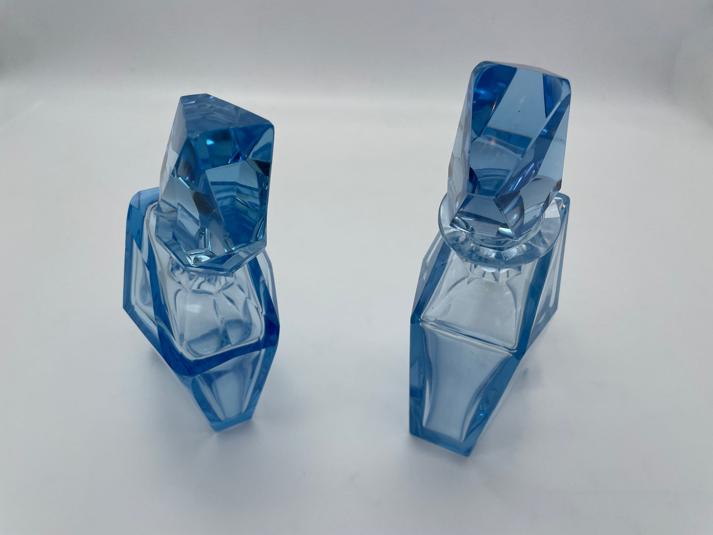 Close-up view of a pair of vintage blue glass decanters highlighting the geometric faceted glass stoppers.