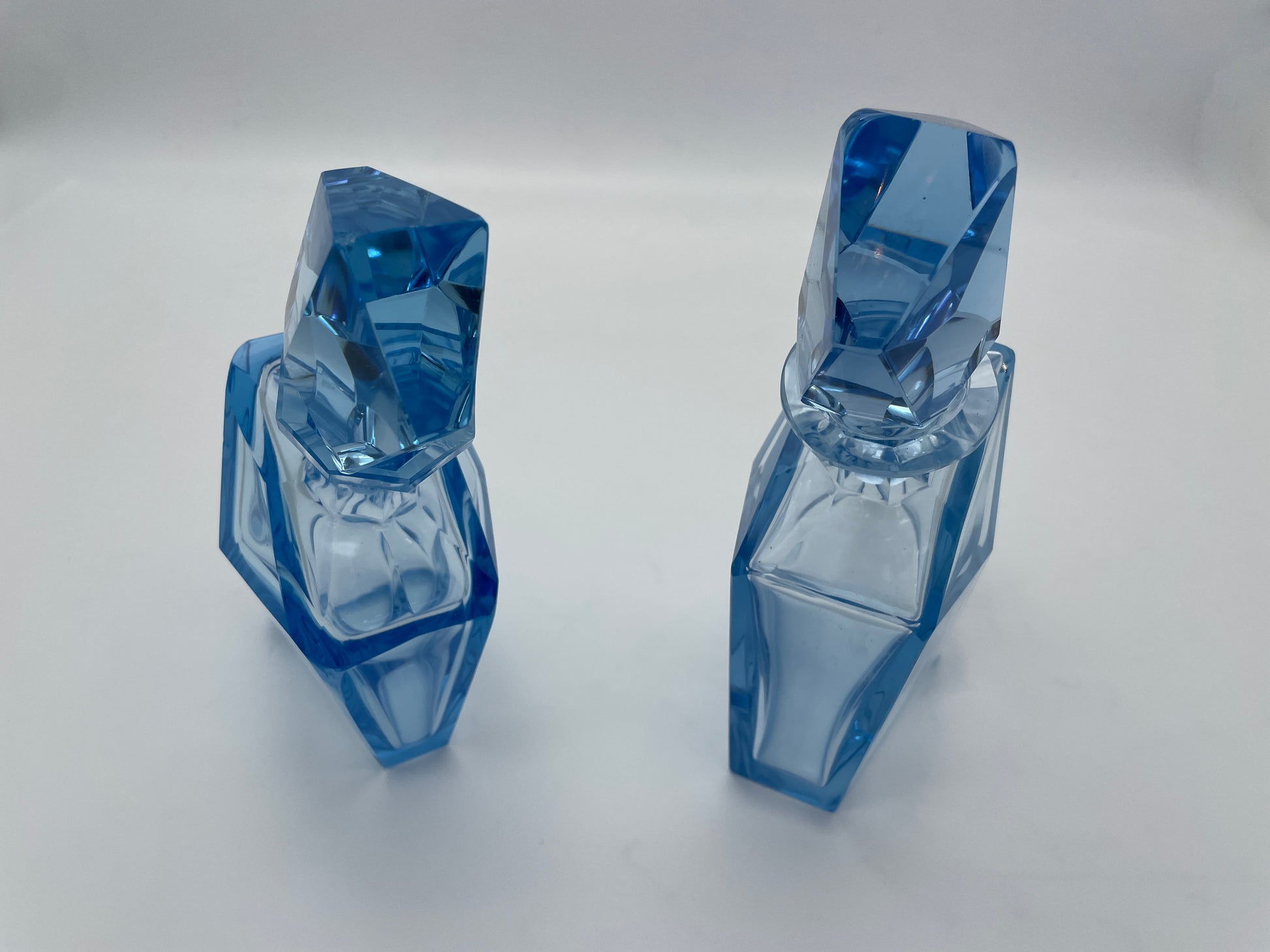 Close-up view of a pair of vintage blue glass decanters highlighting the geometric faceted glass stoppers.