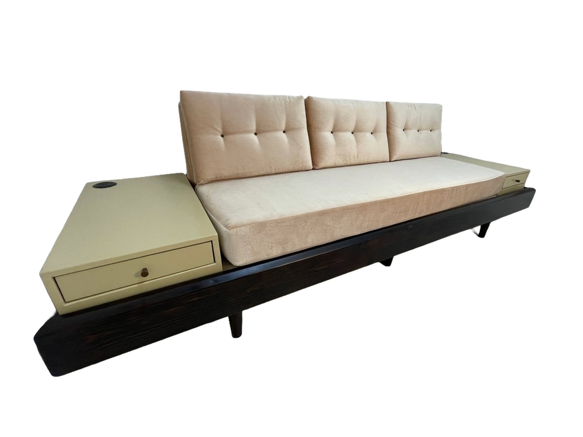 Custom daybed sofa featuring blush upholstered cushions, integrated side tables with drawers, and a dark wood frame viewed from the left angle.