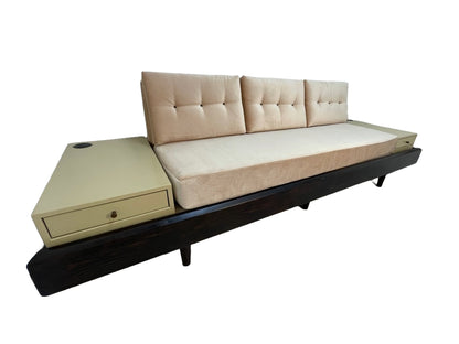 Custom daybed sofa featuring blush upholstered cushions, integrated side tables with drawers, and a dark wood frame viewed from the left angle.