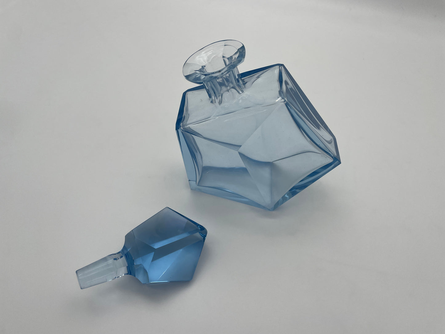 Decorative vintage blue glass decanter with removable faceted stopper, ideal for a home bar or display cabinet.