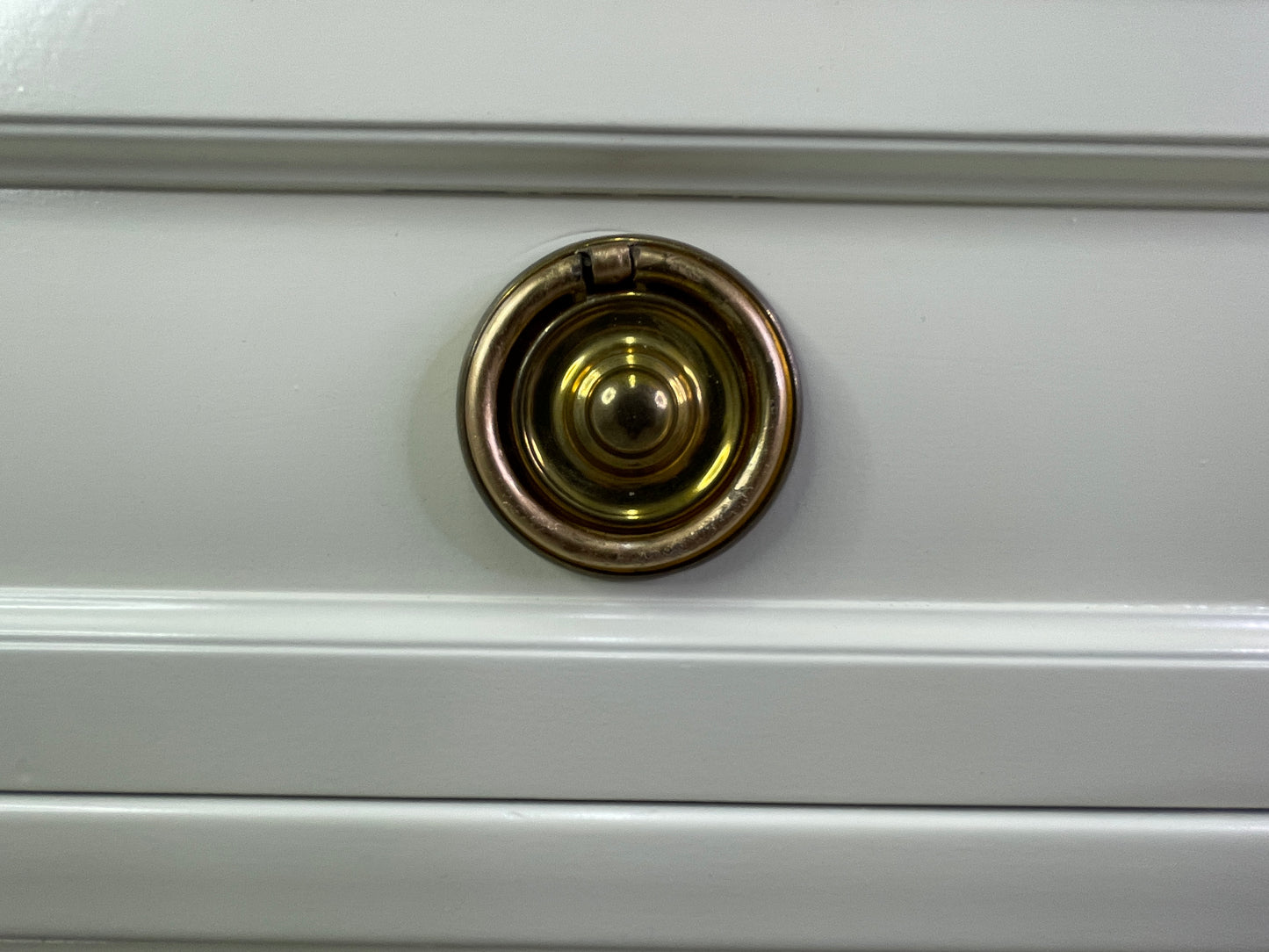 Close-up of brass hardware on American of Martinsville dresser with off-white lacquer round
