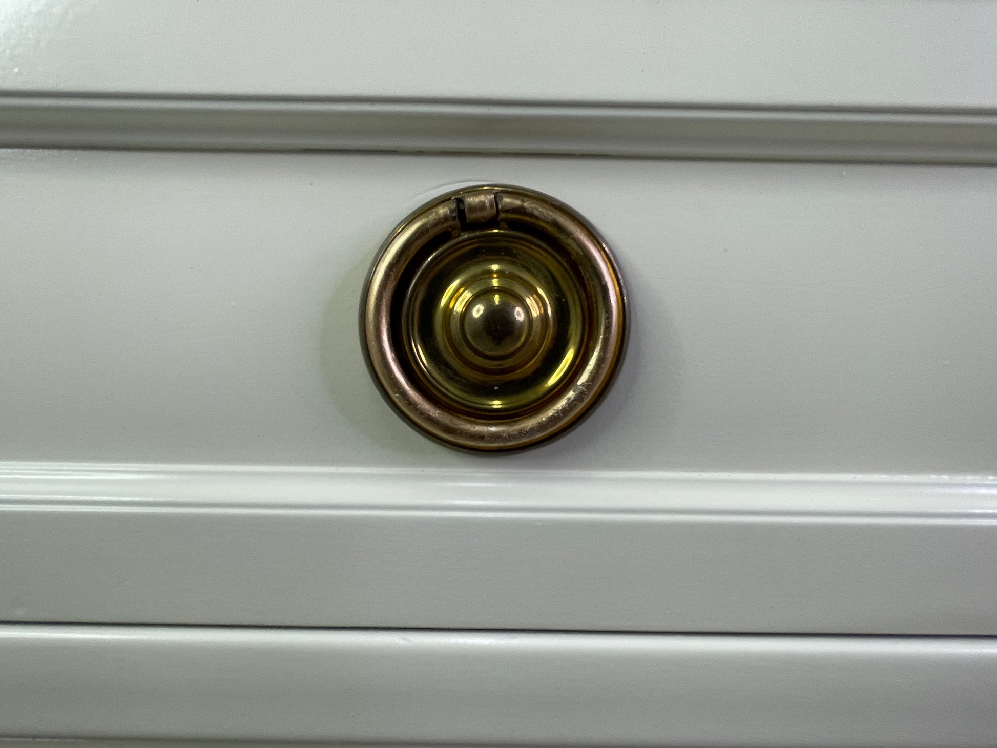 Close-up of brass hardware on American of Martinsville dresser with off-white lacquer round
