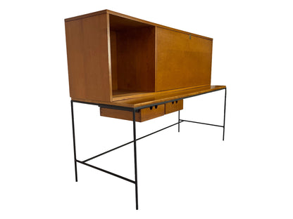 Rear three-quarter view of Paul McCobb Planner Group secretary desk in maple with minimalist black iron frame and sliding cabinet storage, American mid-century modern design.
