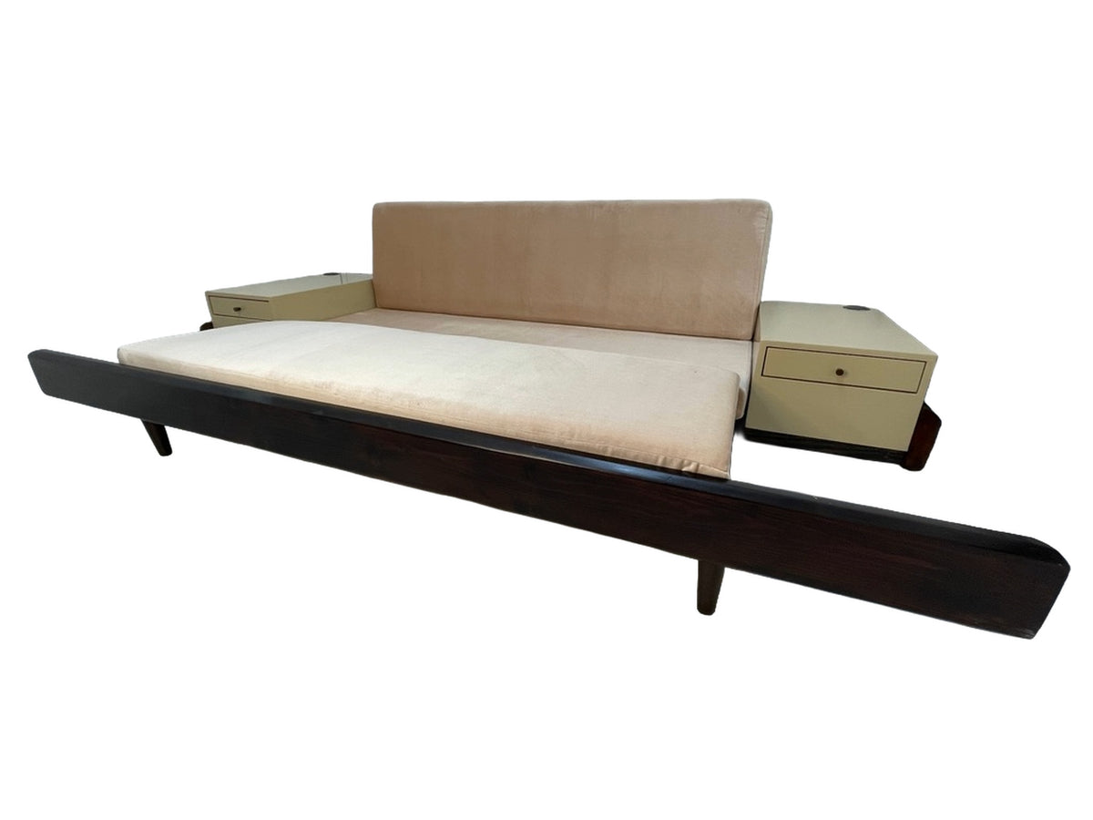 Convertible sleeper sofa with integrated side tables and blush upholstery displayed in open bed configuration.