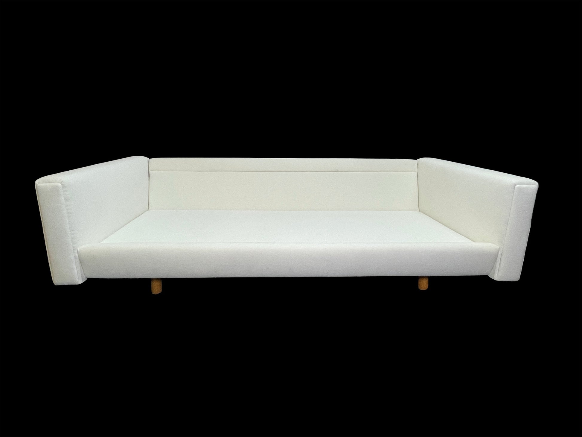 Minimalist architectural white upholstered daybed sofa with deep lounge proportions and angled arms.