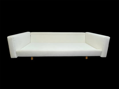 Minimalist architectural white upholstered daybed sofa with deep lounge proportions and angled arms.