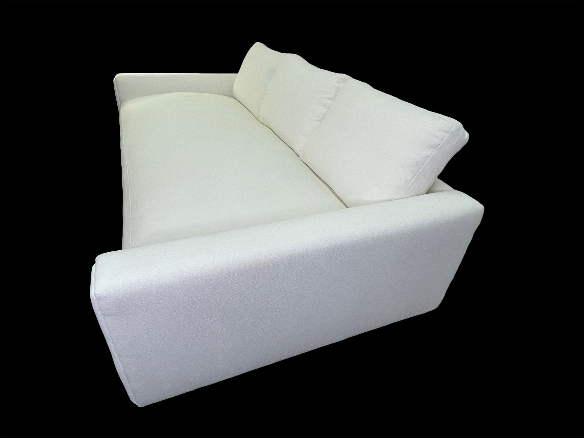 Rear angled view of custom white upholstered daybed with oversized back cushions and minimalist silhouette.