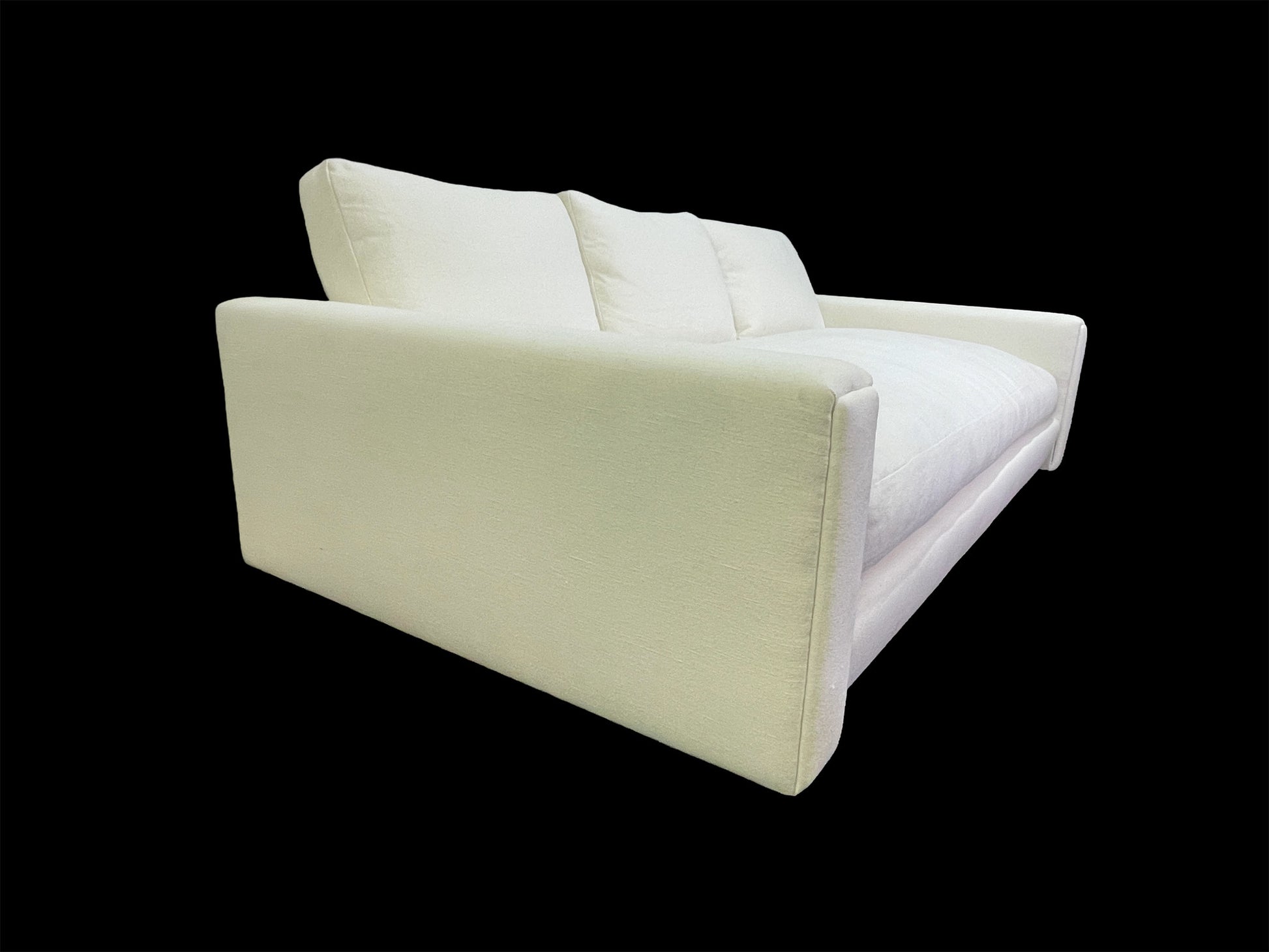 Side profile of modern white upholstered daybed featuring oversized arms and minimalist lounge silhouette.