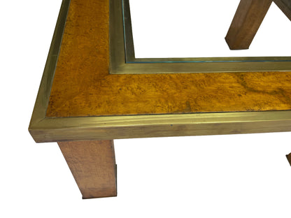Close-up detail of olive ash burl veneer, brass banding, recessed glass insert, and architectural leg construction.
