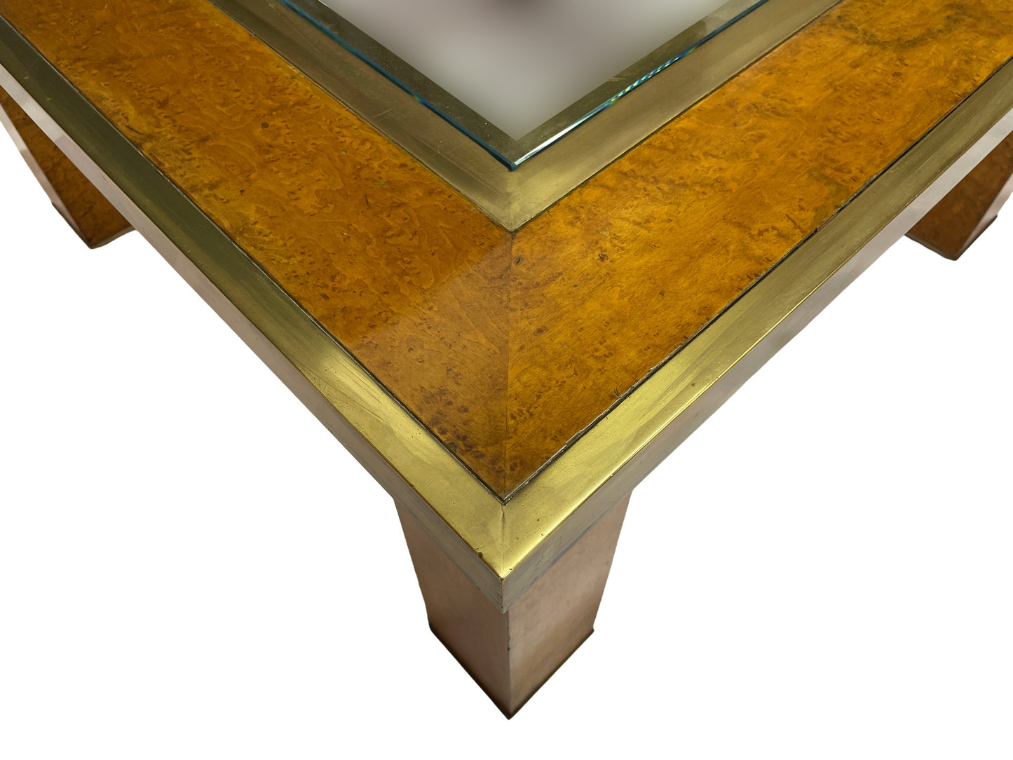 Close-up corner detail showing olive ash burl veneer, brass trim, and recessed glass insert.
