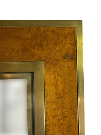 Close-up of olive ash burl veneer and aged brass trim showing natural grain and patina.