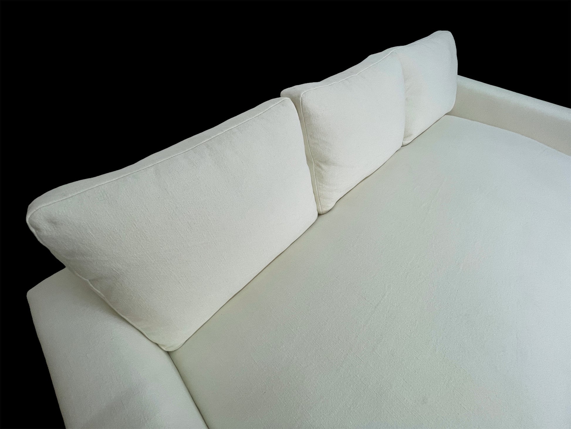 Overhead angled view of modern white upholstered daybed featuring oversized deep seating and sculptural arms.