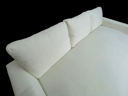Overhead angled view of modern white upholstered daybed featuring oversized deep seating and sculptural arms.