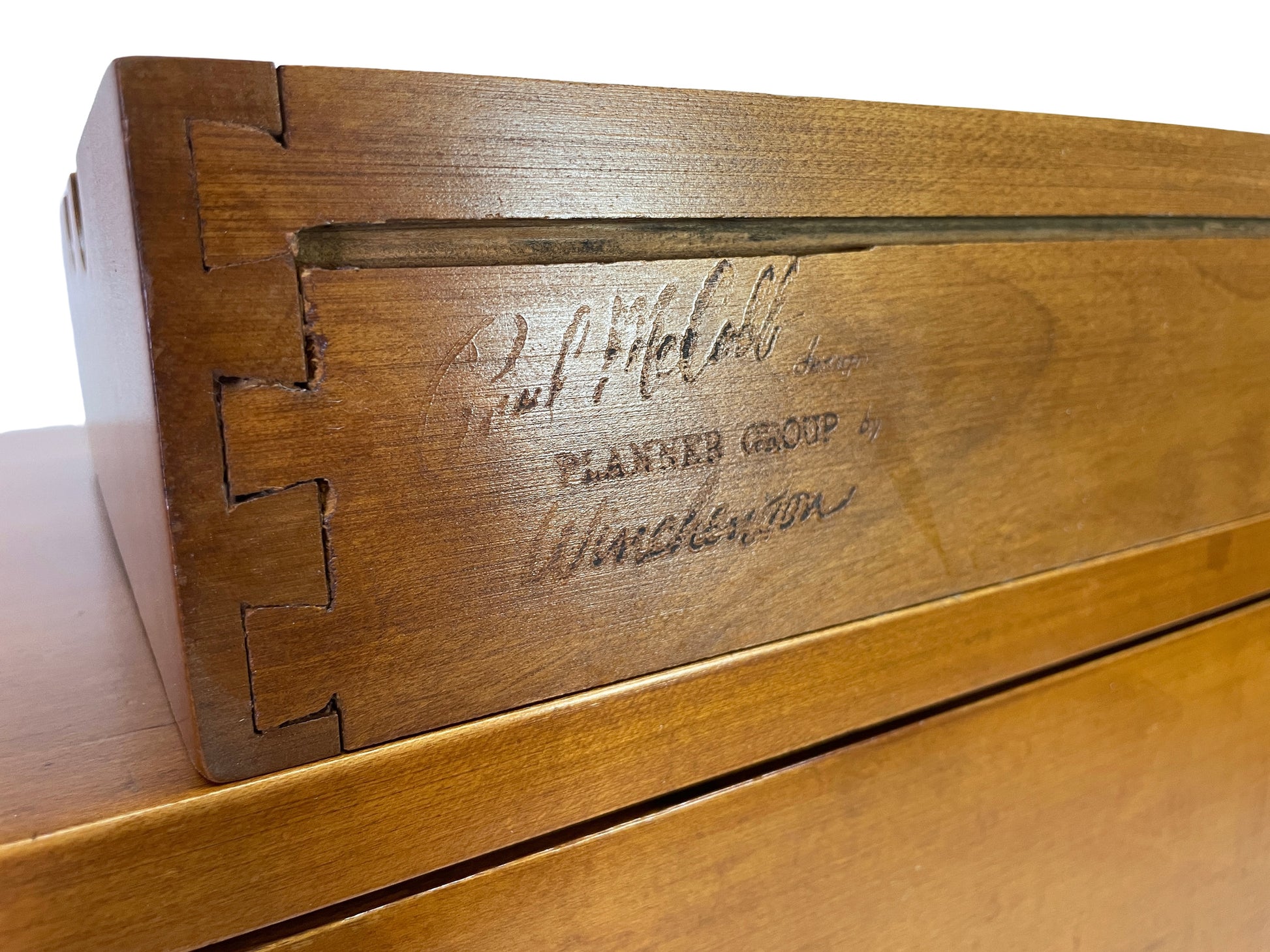Close-up detail of the branded Planner Group by Winchendon manufacturer marking on the exterior side of a maple desk drawer designed by Paul McCobb.