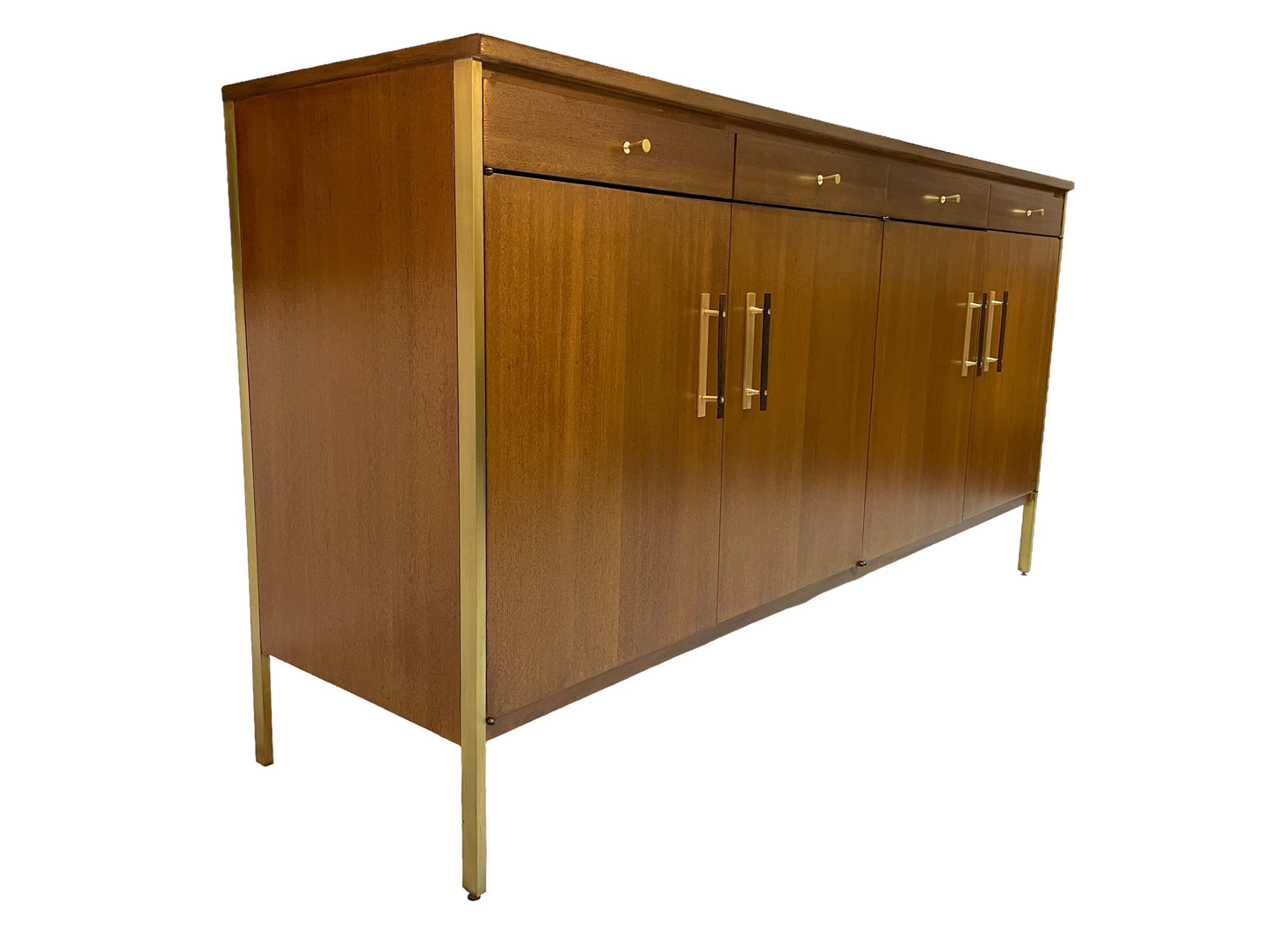 Angled left-side view of a Paul McCobb Calvin Group credenza in ribbon mahogany featuring brass trim, brass legs, and original modernist cabinet design.