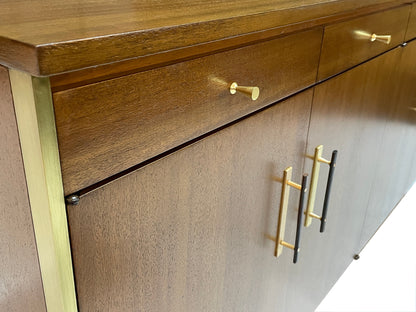 Detail view of ribbon mahogany grain, brass drawer pull, and brass-trimmed case on a restored Paul McCobb Calvin Group credenza from the 1960s.