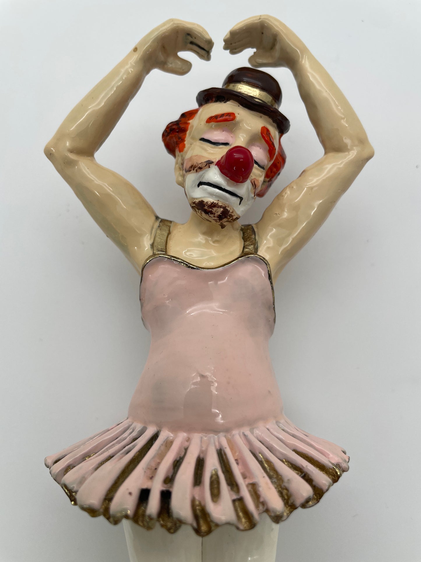 Close-up of the expressive face and upper body of a vintage Ron Lee ballerina clown sculpture with pink tutu, hand-painted finish, and gold-plated accents.