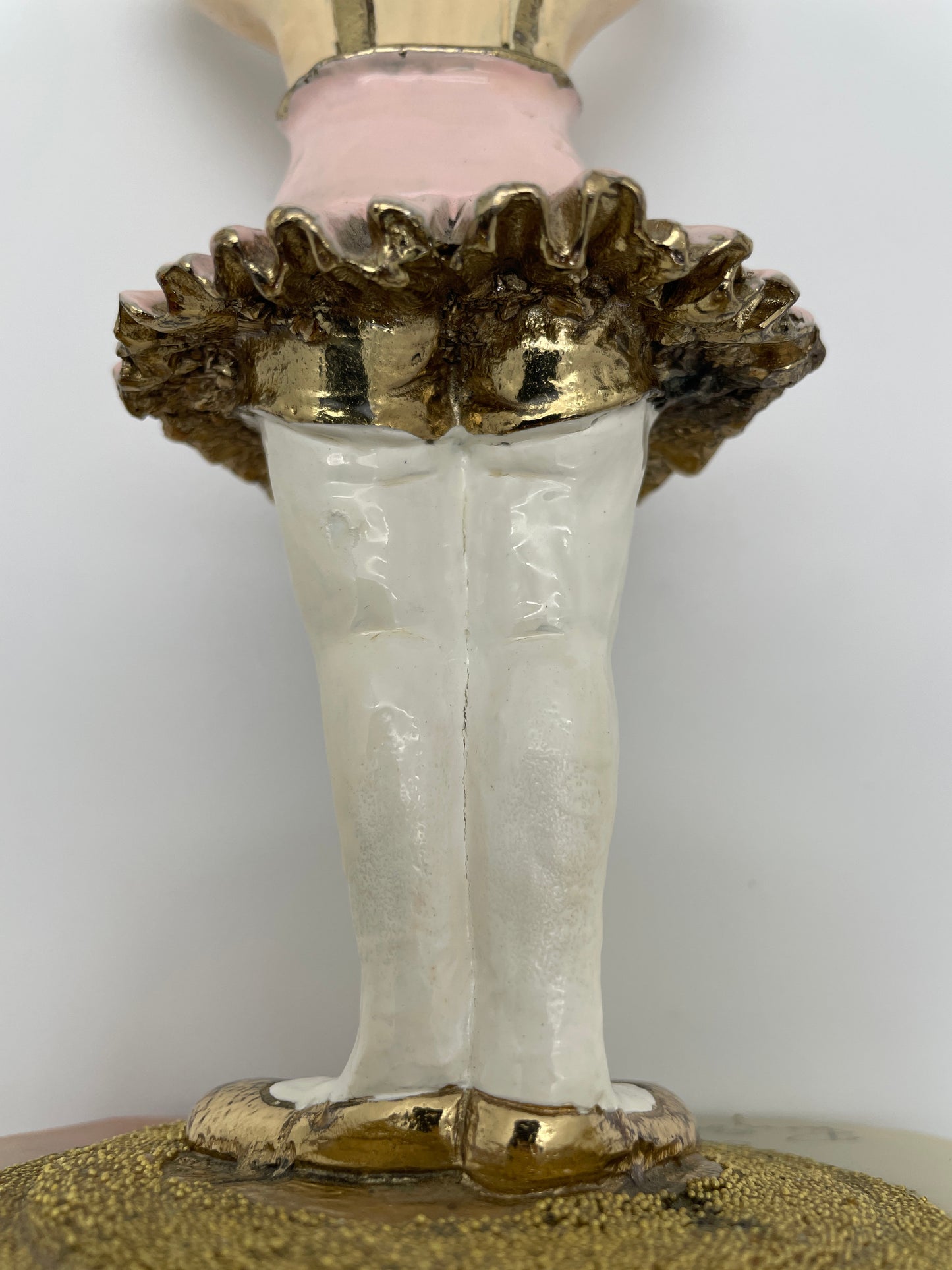 Close-up of the gold-plated ballet shoes, textured stage, and pink tutu on a signed Ron Lee ballerina clown sculpture.