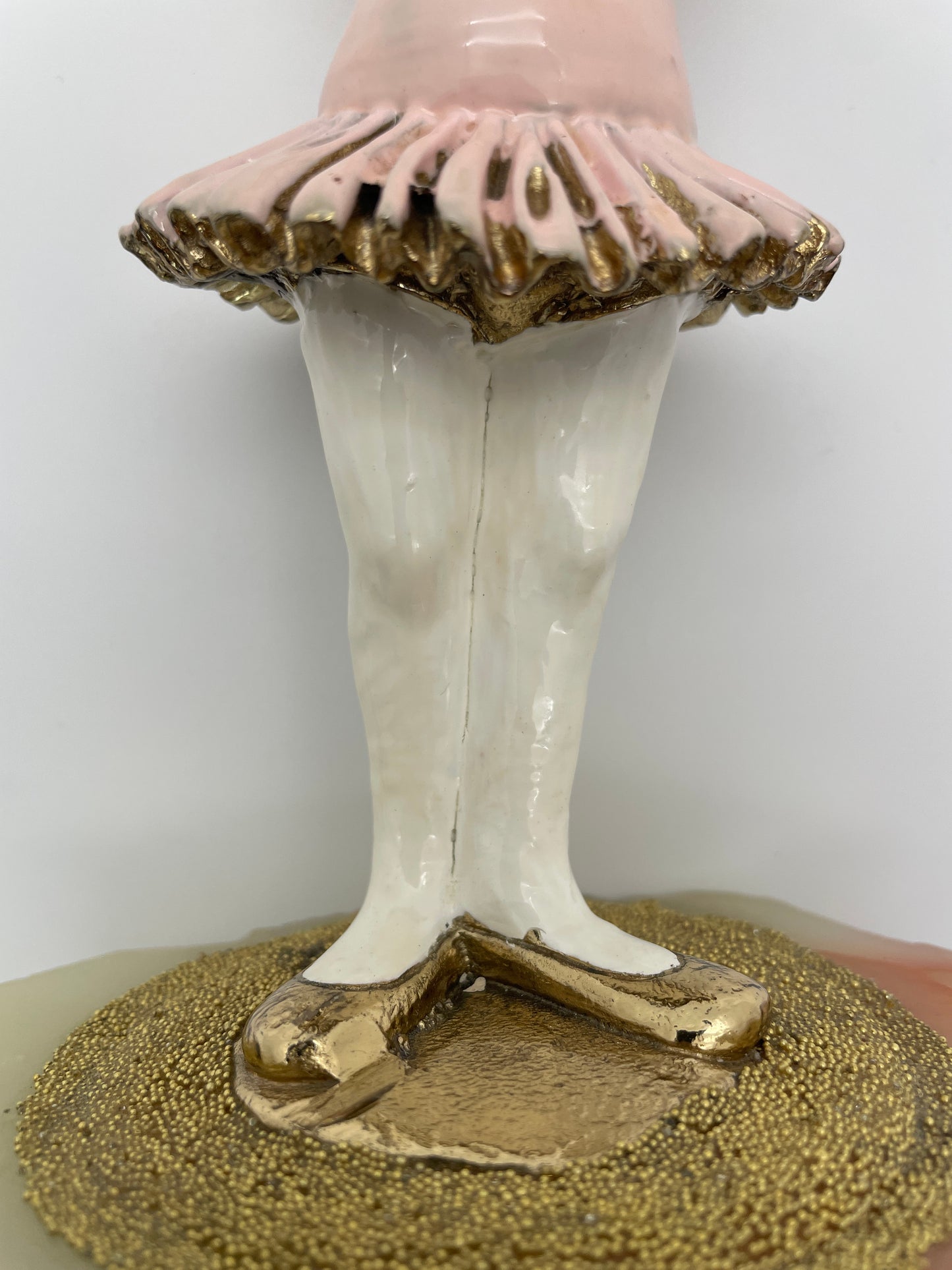 Close-up of the pink tutu, gold-plated ballet shoes, and textured stage on a vintage Ron Lee ballerina clown sculpture.
