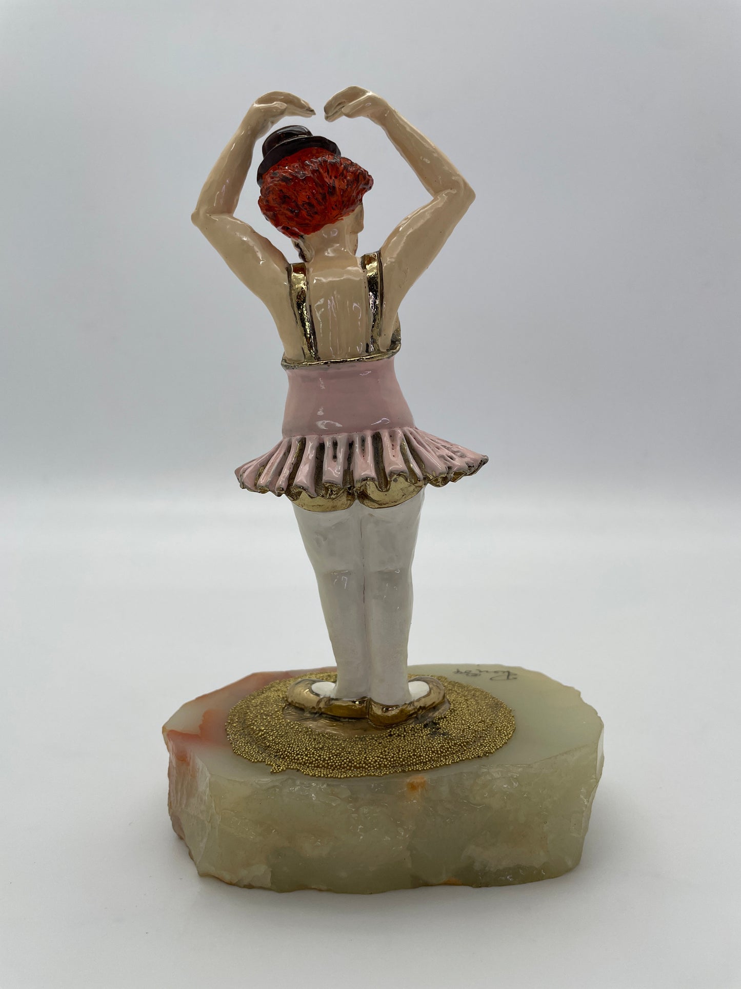 Rear view of a vintage Ron Lee ballerina clown sculpture with pink tutu, 24K gold-plated accents, and natural onyx base.