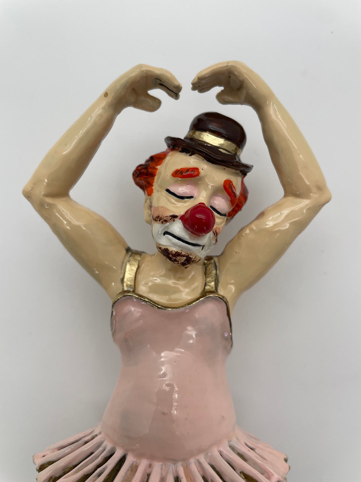 Close-up of the expressive face of a vintage Ron Lee ballerina clown sculpture with hand-painted features and bowler hat.