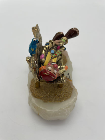 Side view of a vintage Ron Lee clown figurine resting on a park bench with a blue bird, hand-painted details, oversized clown shoes, and natural onyx base.