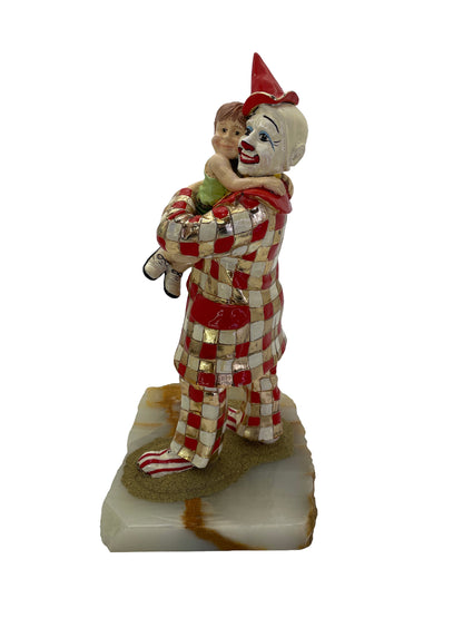 Side view of a vintage Ron Lee figurative sculpture showing a child embracing a clown on a natural onyx base.