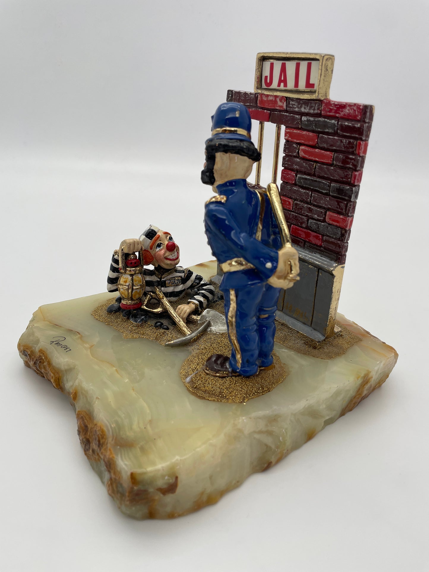 Rear three-quarter view of the Ron Lee Great Escape sculpture featuring a police clown, prisoner clown, jail wall, and polished natural onyx base.