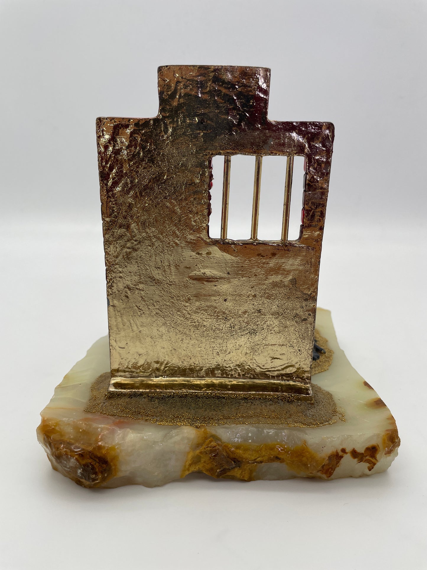 Rear view of the Ron Lee Great Escape clown sculpture showing the back of the jail wall, natural onyx base, and metal jail bars.