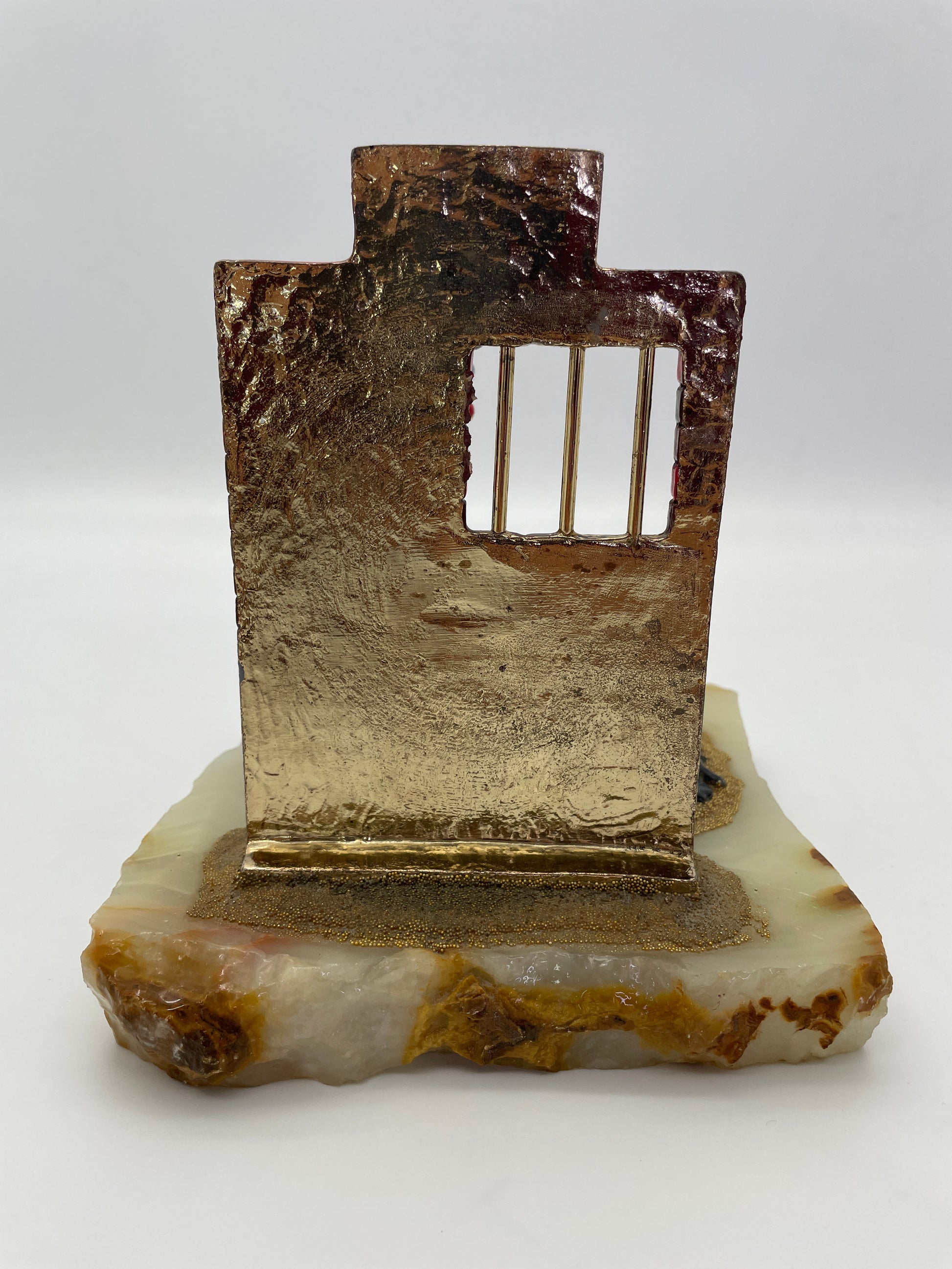 Rear view of the Ron Lee Great Escape clown sculpture showing the back of the jail wall, natural onyx base, and metal jail bars.