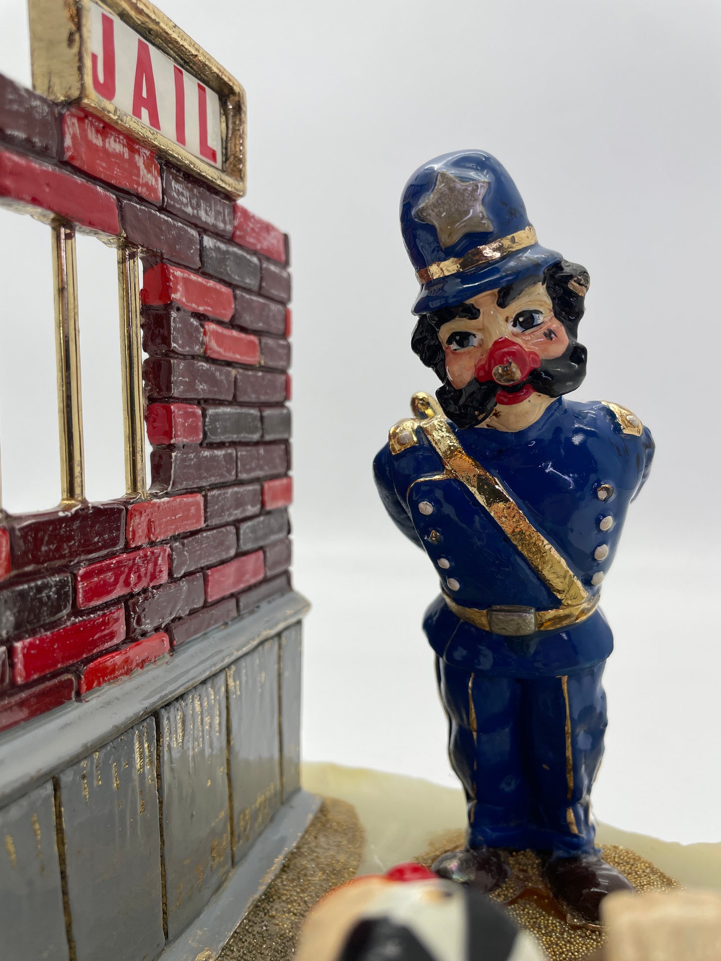 Close-up of the hand-painted police clown beside the jail wall in Ron Lee’s Great Escape sculpture with 24K gold-plated accents.