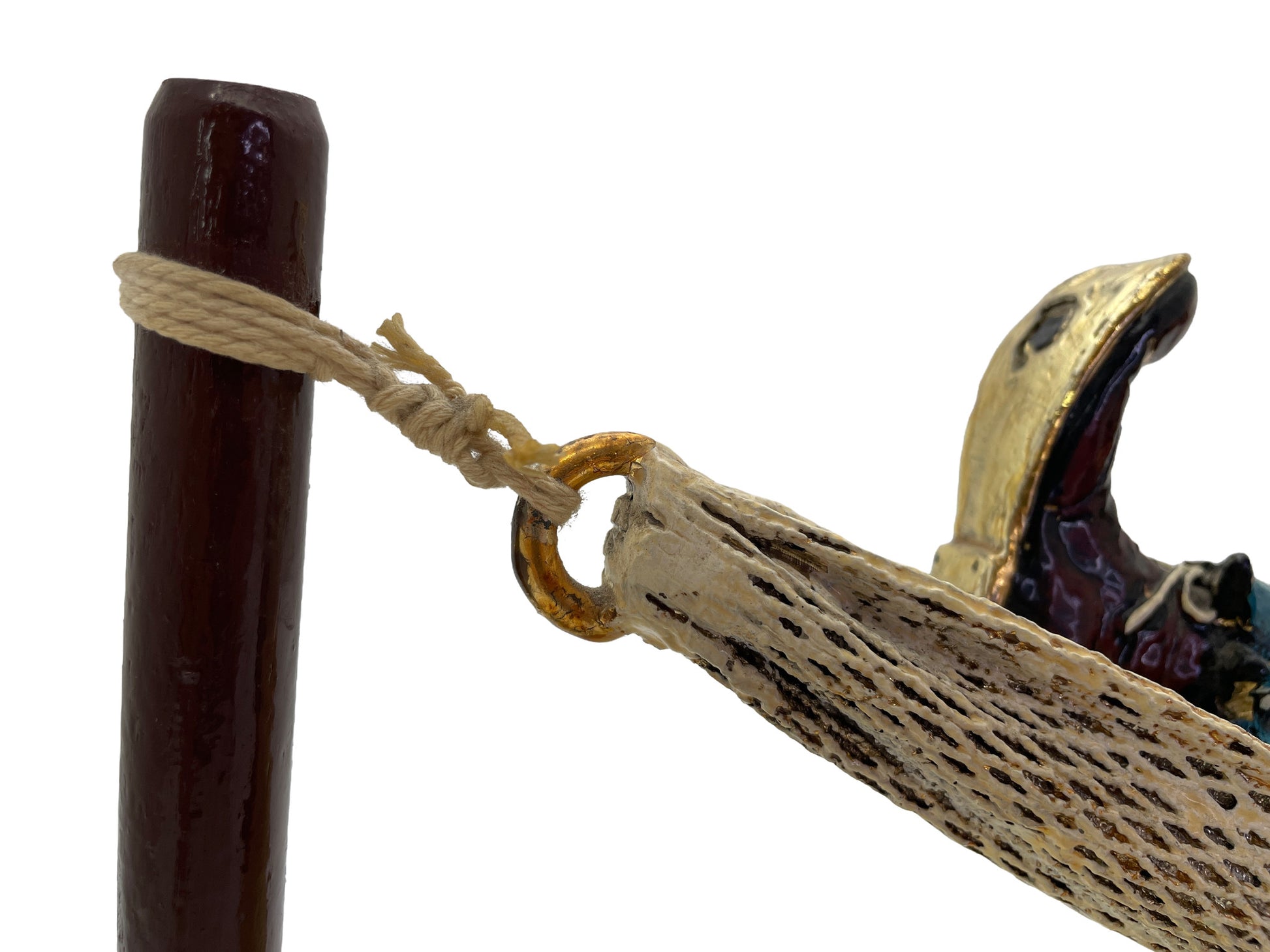 Close-up of the rope, brass-tone ring, and woven hammock attachment on a signed Ron Lee clown sculpture with a natural onyx base.