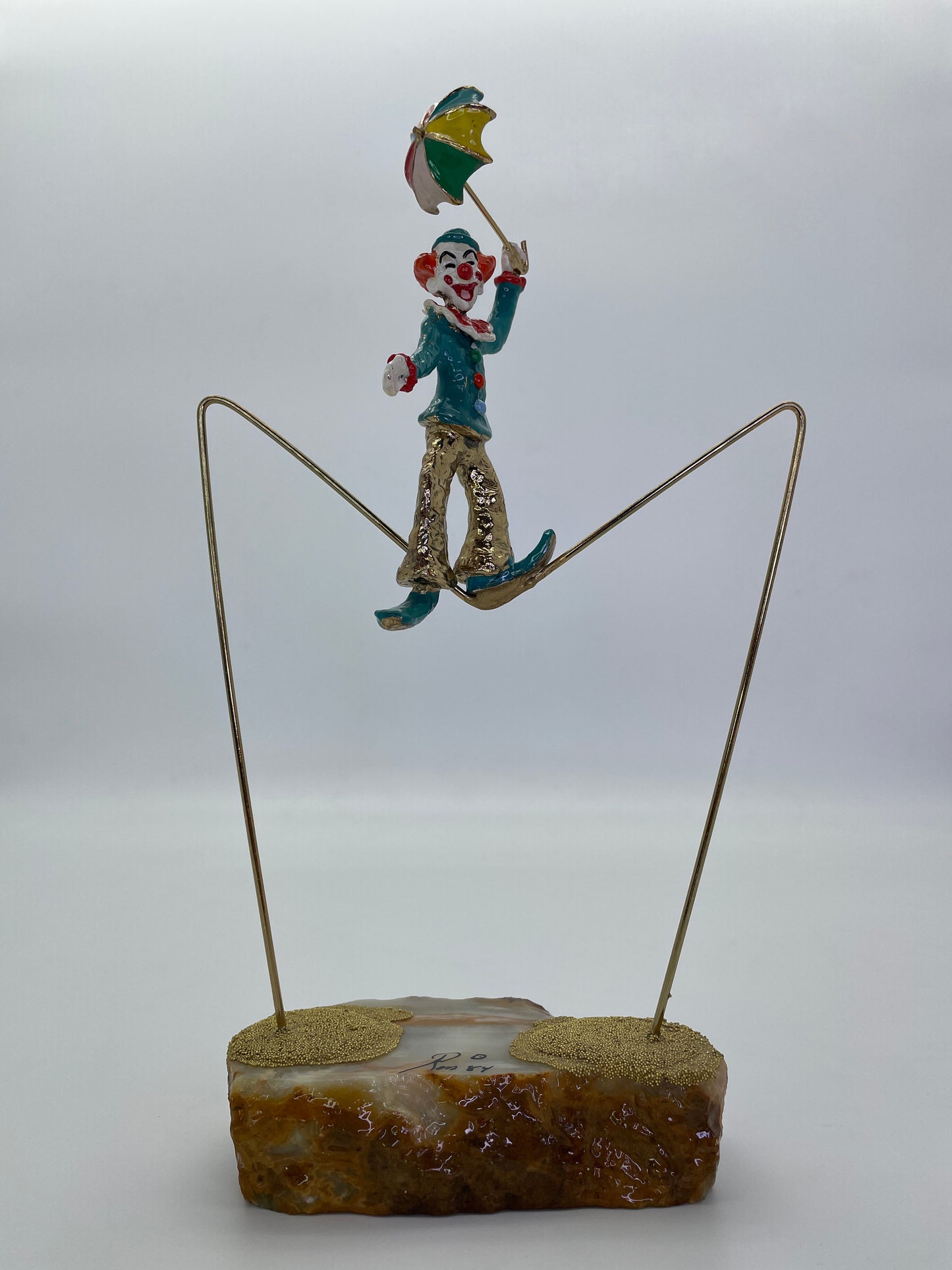 Full front view of a vintage Ron Lee high wire clown sculpture with suspended brass wire.