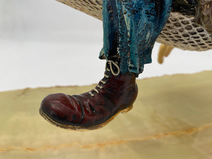 Close-up of the hand-painted boot and trouser detail on a signed 1988 Ron Lee hobo clown sculpture resting in a hammock on a natural onyx base.