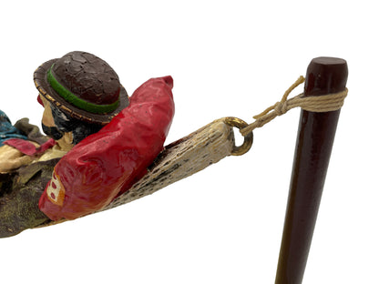 Close-up of the woven hammock attachment, rope, and brass-tone ring on a signed 1988 Ron Lee hobo clown sculpture with natural onyx base.