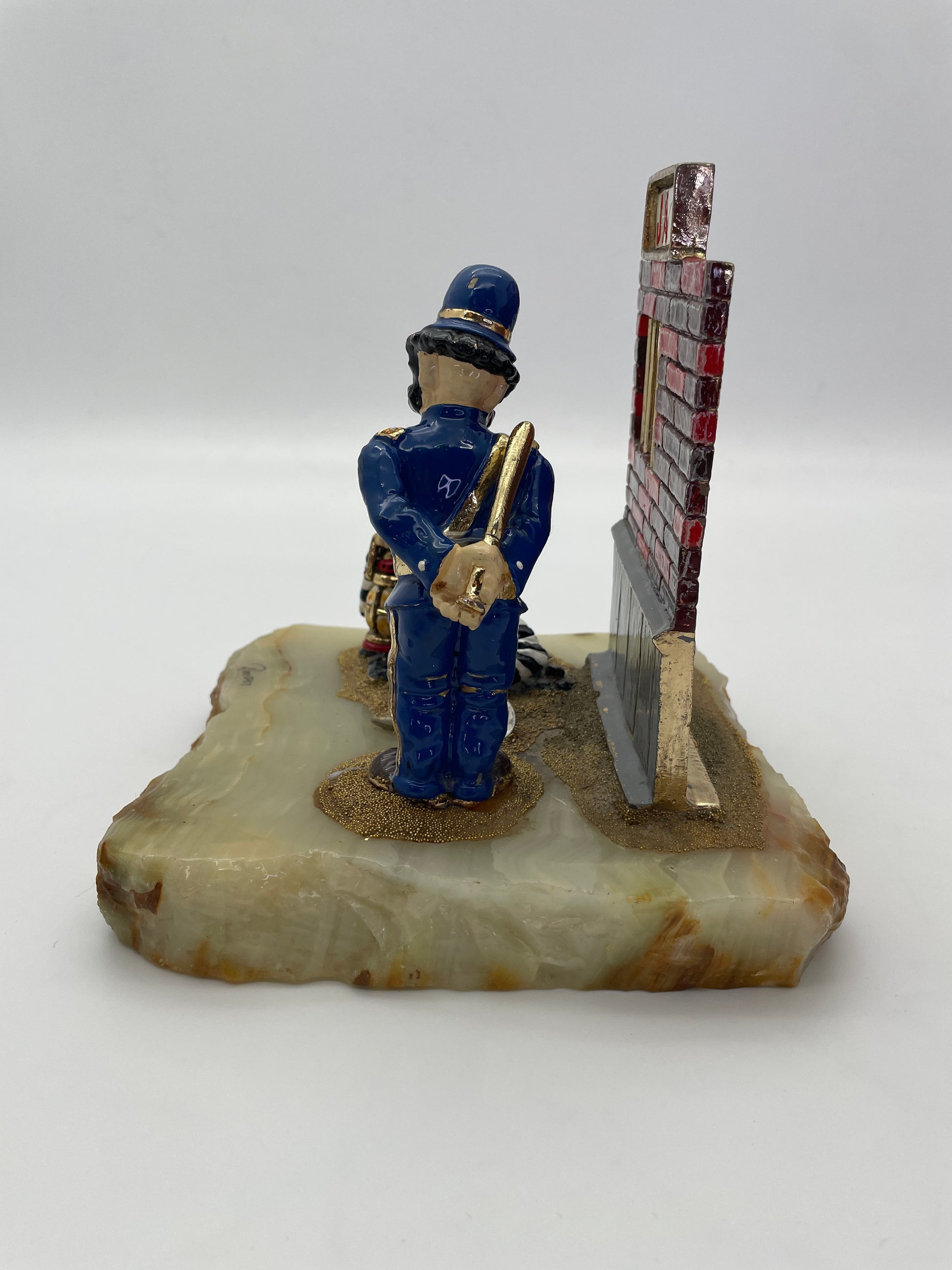 Right side view of Ron Lee Great Escape sculpture showing the police clown with baton, jail wall, and polished natural onyx base.