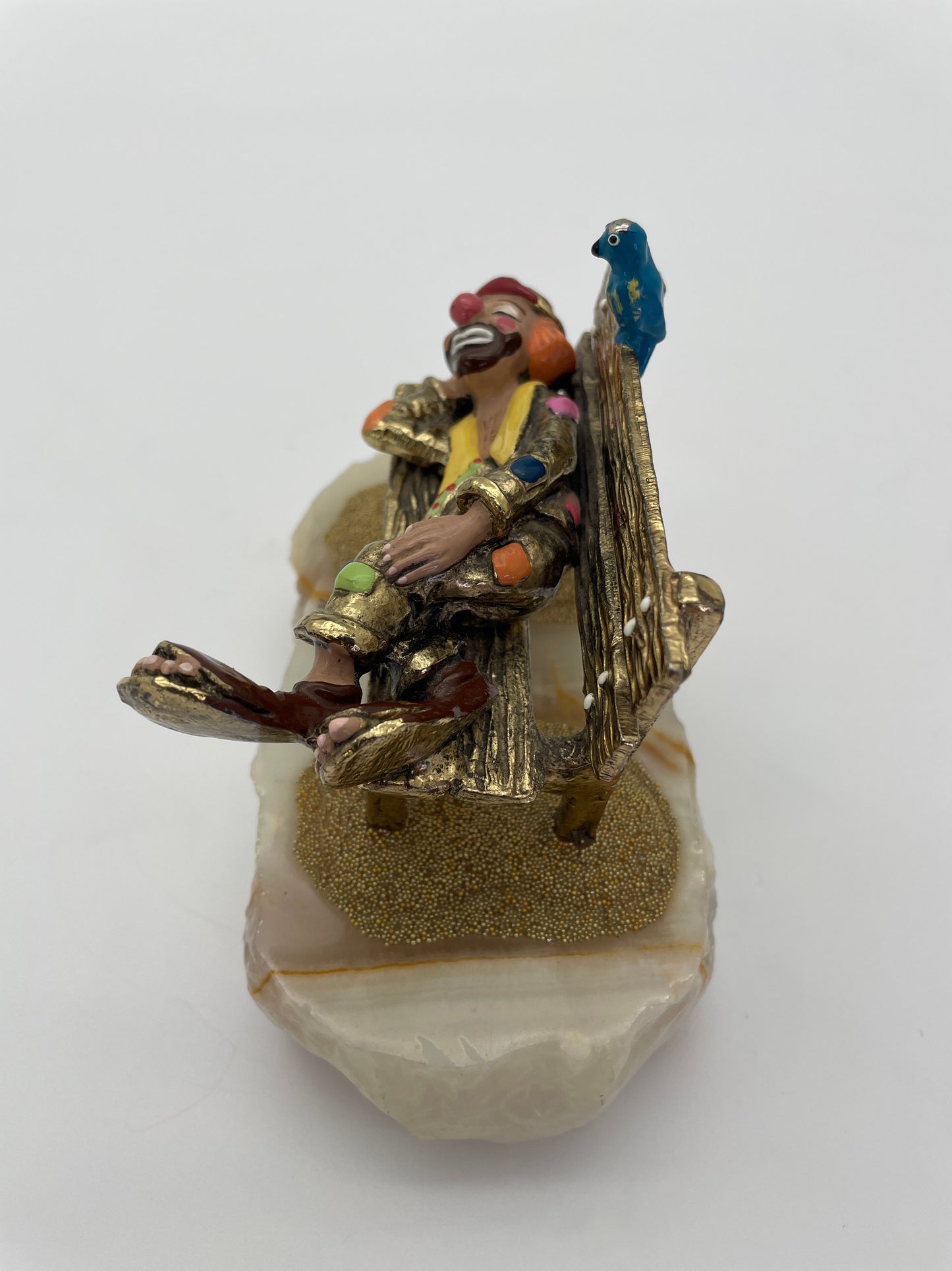 Angled view of a signed Ron Lee sleeping clown circus figurine featuring a textured park bench, blue bird, 24K gold-plated finish, and natural onyx base.