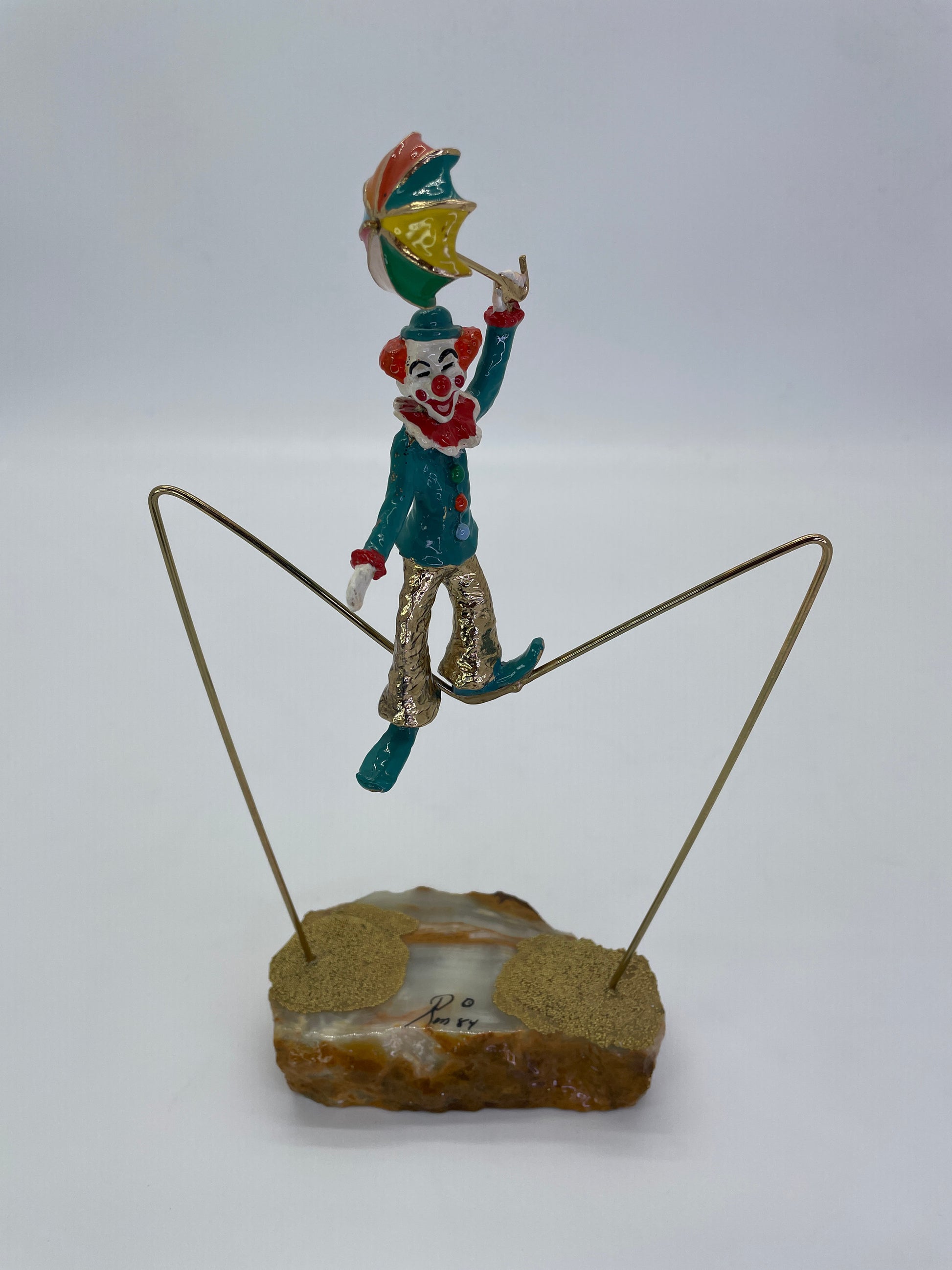Three-quarter front view of a Ron Lee tightrope walker clown sculpture holding a circus umbrella.