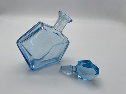 Sculptural vintage blue glass decanter with a matching faceted glass stopper displayed alongside the bottle.